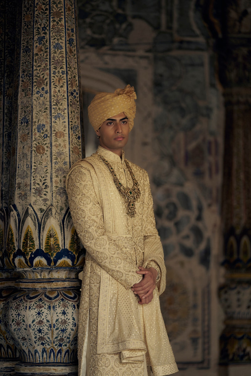 GOLD RAW SILK SHERWANI WITH KURTA AND CHURIDAR WITH AN OPTIONAL WORKED BELT, STOLE AND JUTIS.